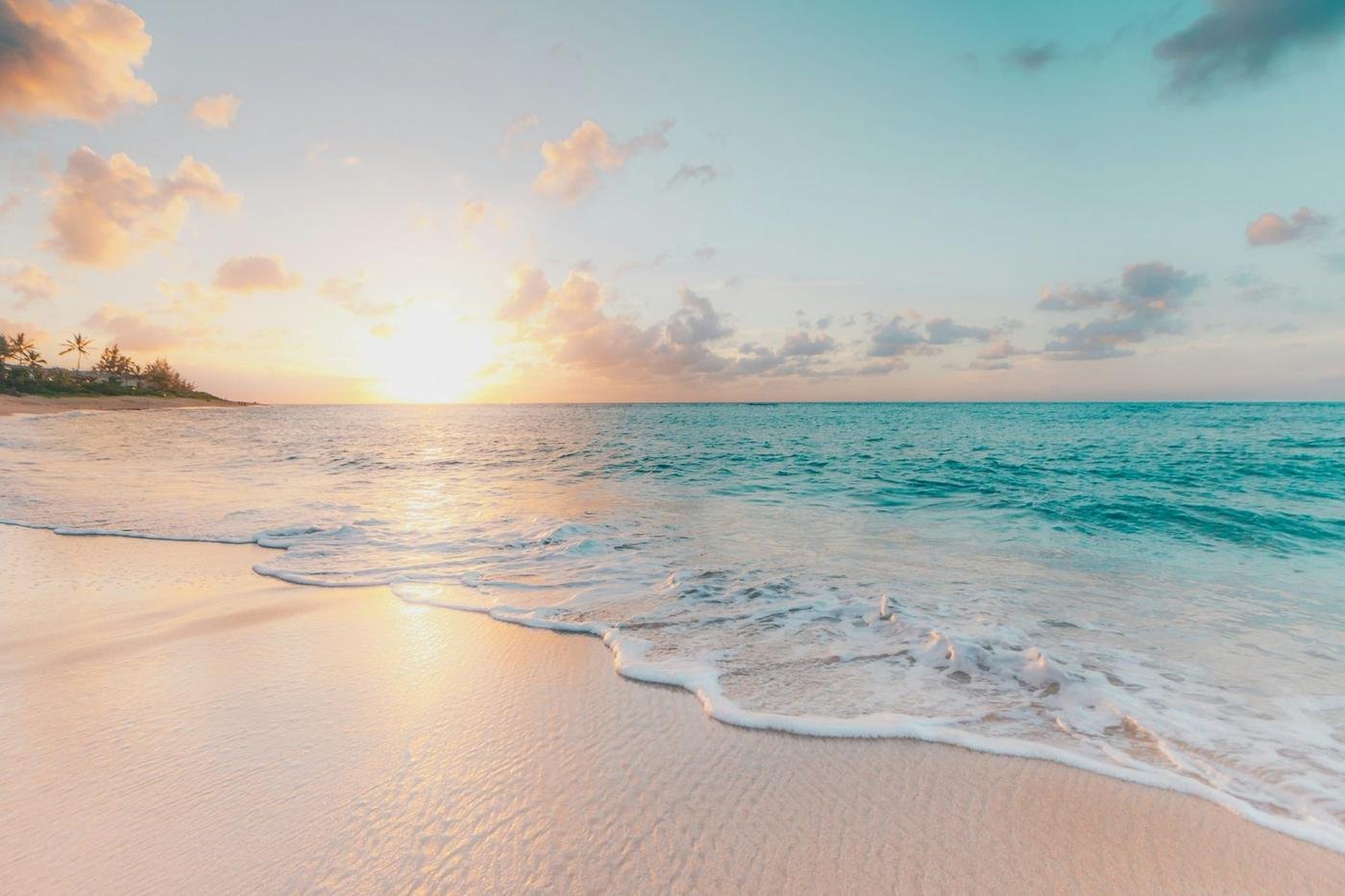 A pale beach and small waves at sunrise