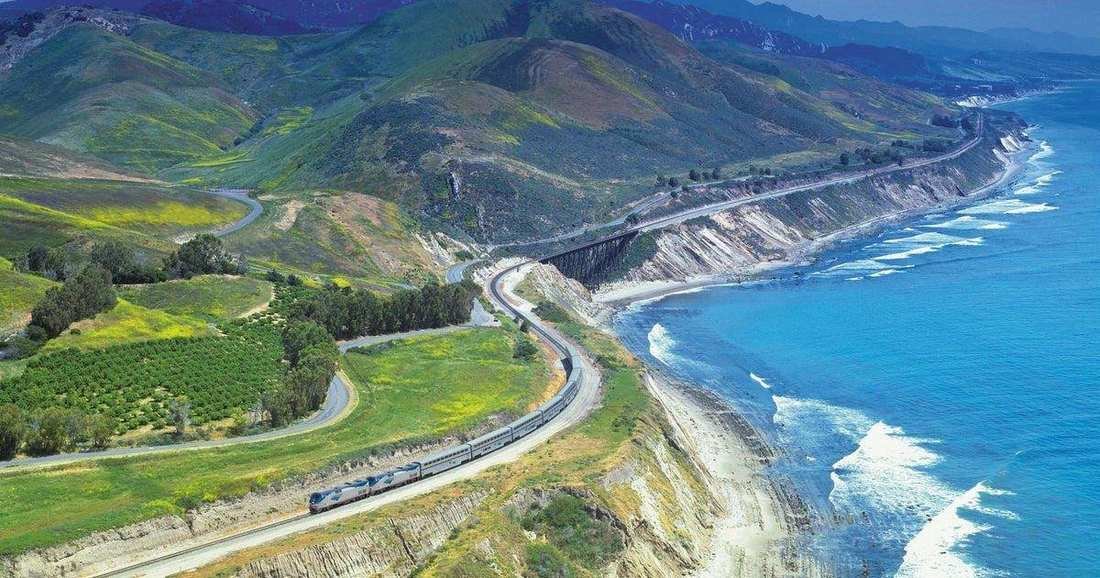 The Coast Starlight on a trestle above the Pacific, with green hills behind