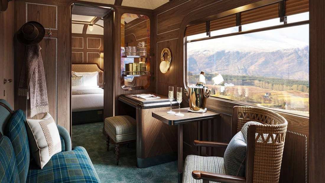 A wood-paneled cabin on the Royal Scotsman, with a bed and a view of hills