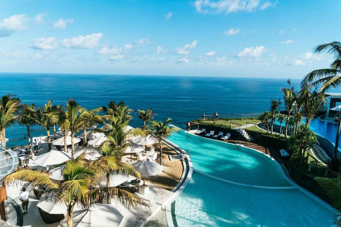 A palm-lined pool above the open ocean