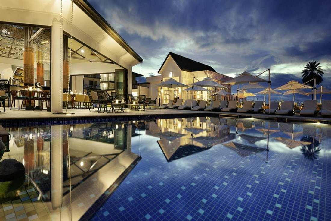 Lounge chairs and a still pool at a resort after dusk