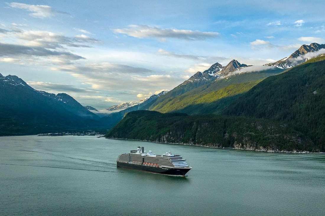 A mid-size cruise ship in a narrow Alaskan channel