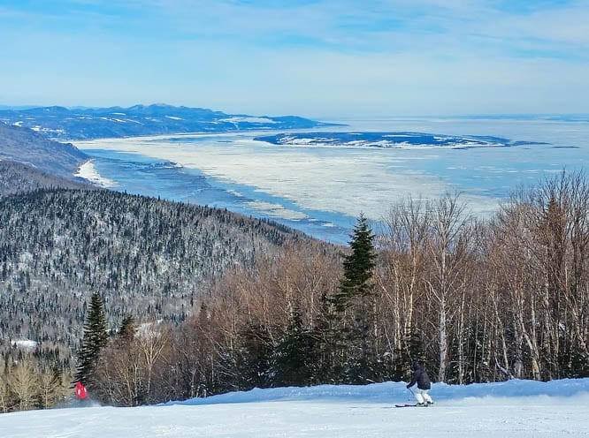 A skier on Le Massif with the frozen St. Lawrence River below