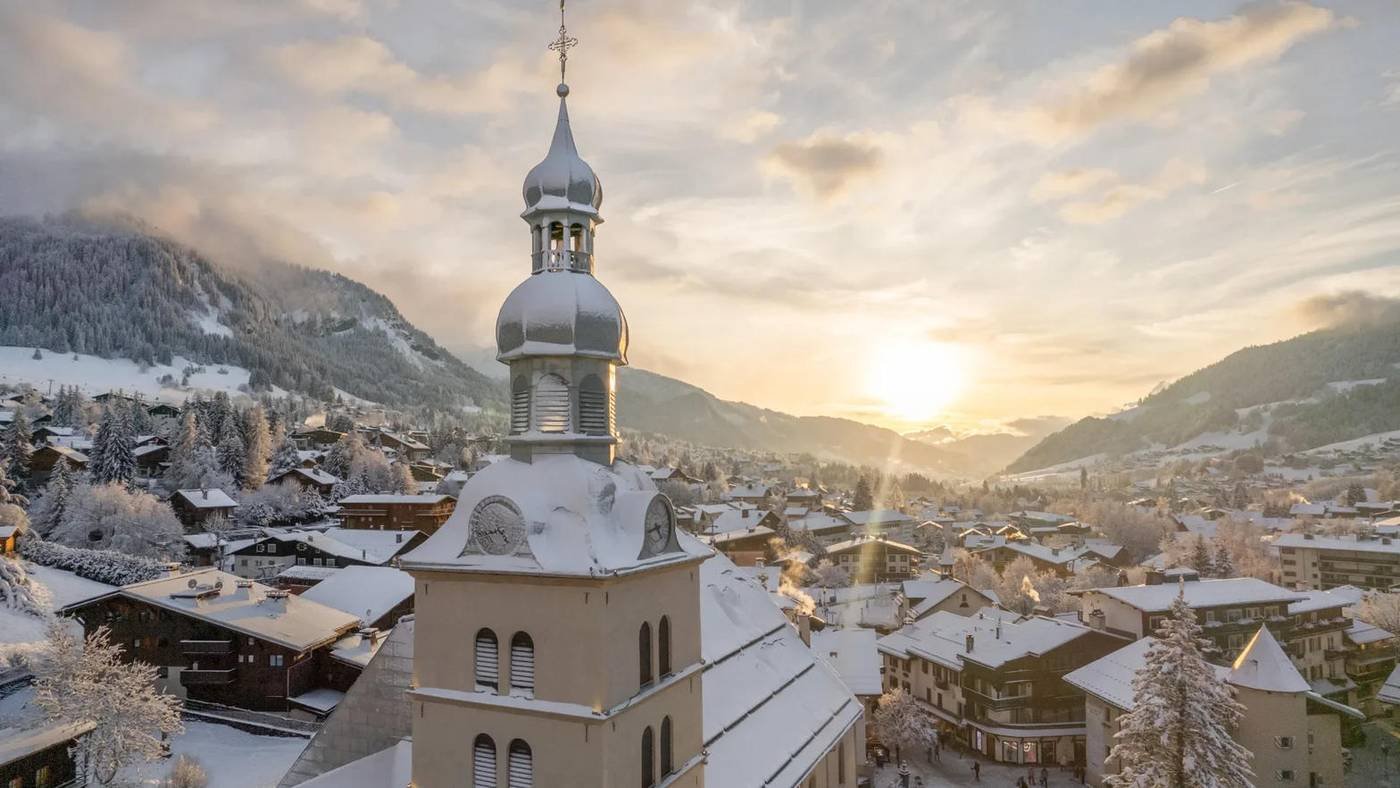 The snow-covered church and village of Megève at sunset